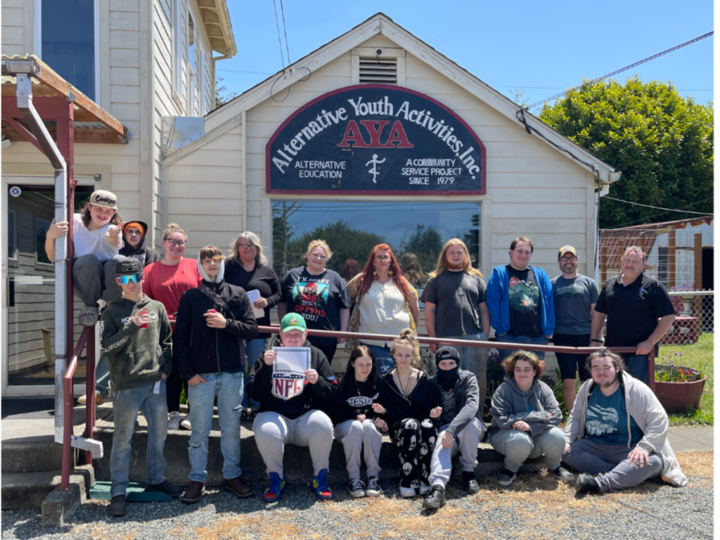 Group photo of staff and students in front of the Alternative Youth Activities, Inc. building.